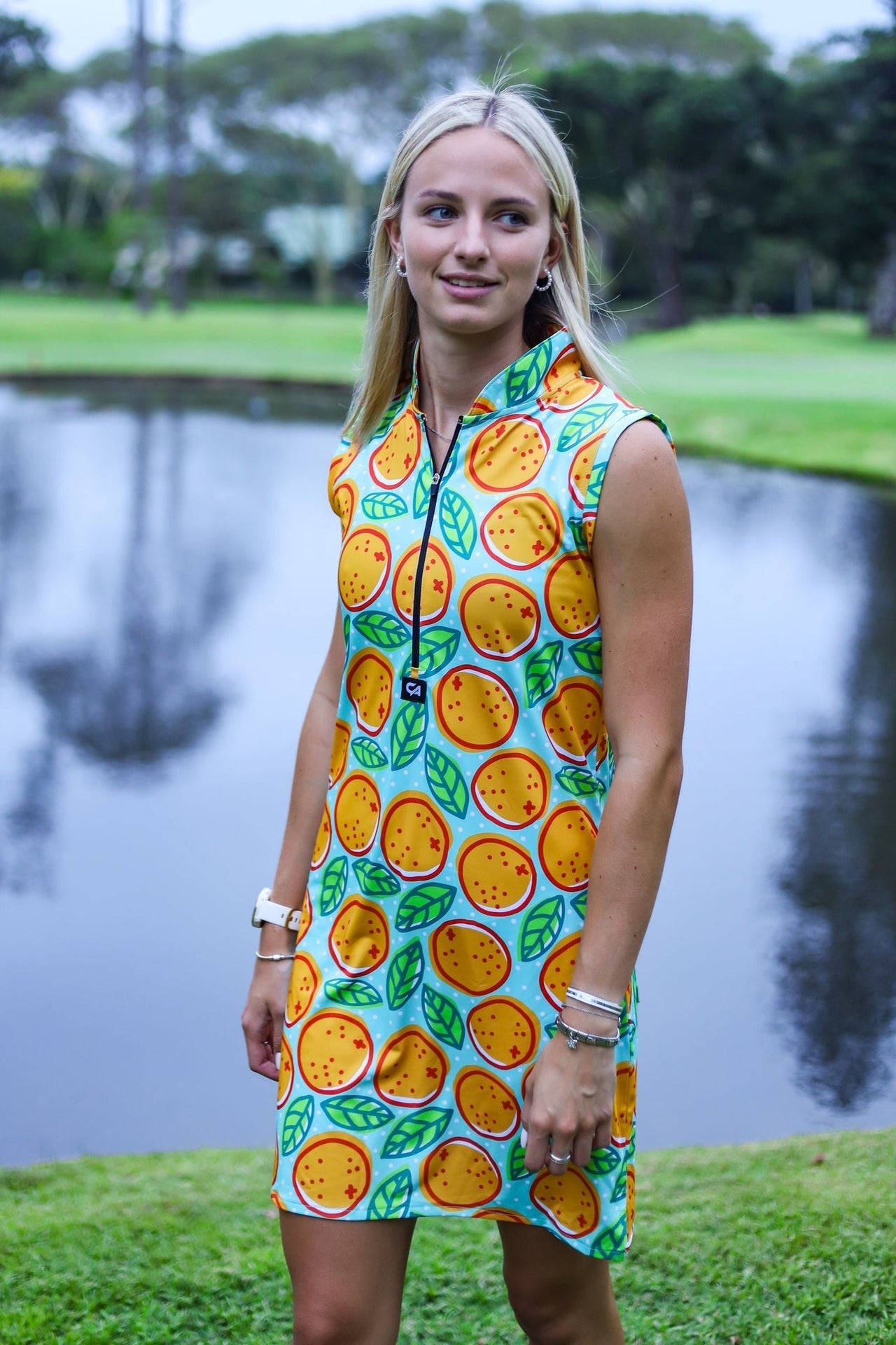 Yellow orange print dress with green leaves and white zipper detail.
